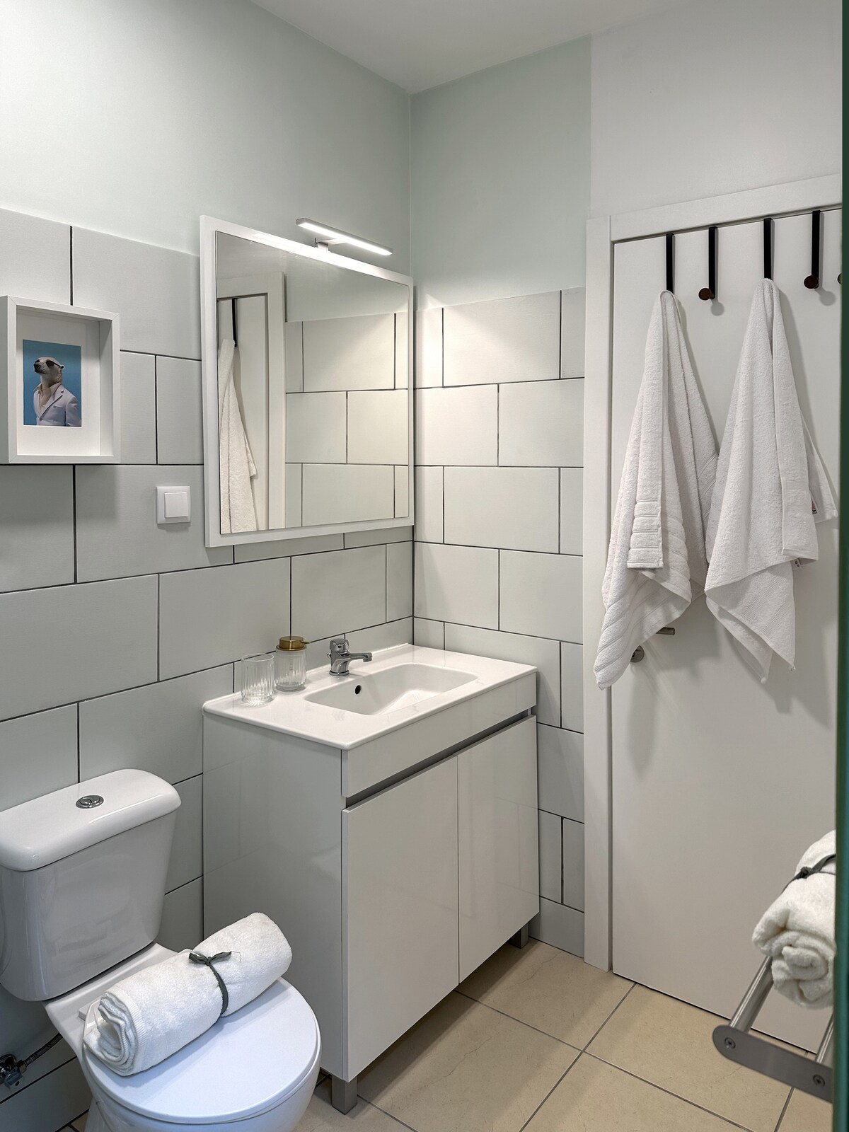 White-tile bathroom with framed art