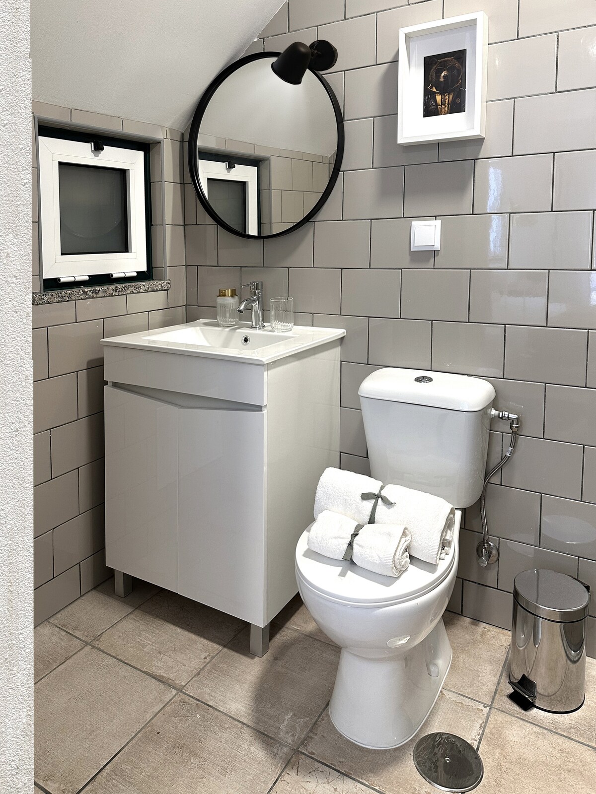 Grey-tile bathroom with round mirror