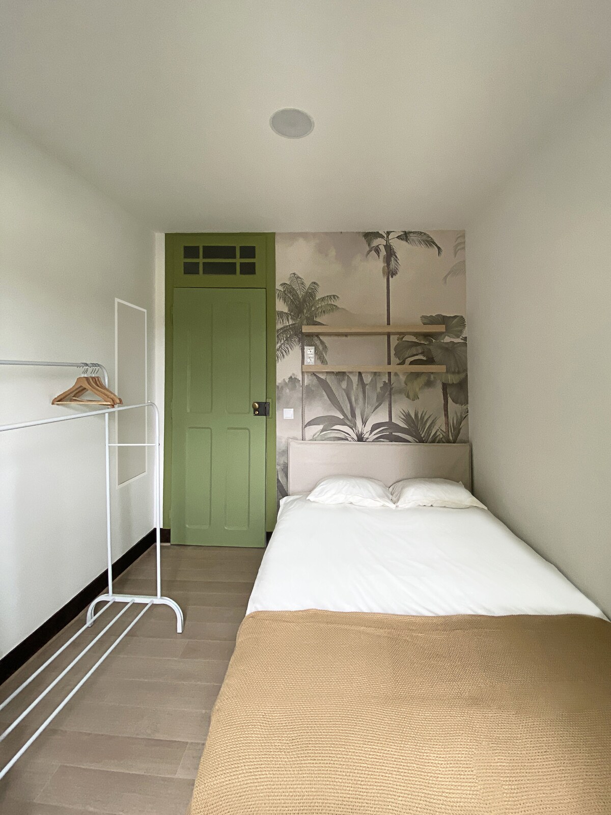 Bedroom with palm wallpaper and green door