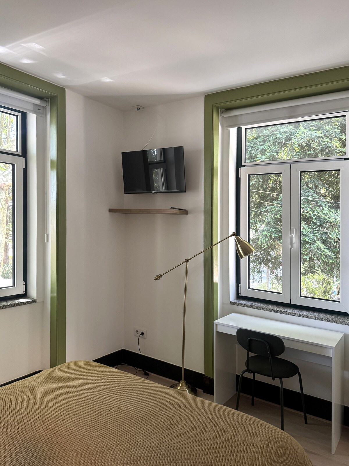 Bedroom with green windows and wall TV